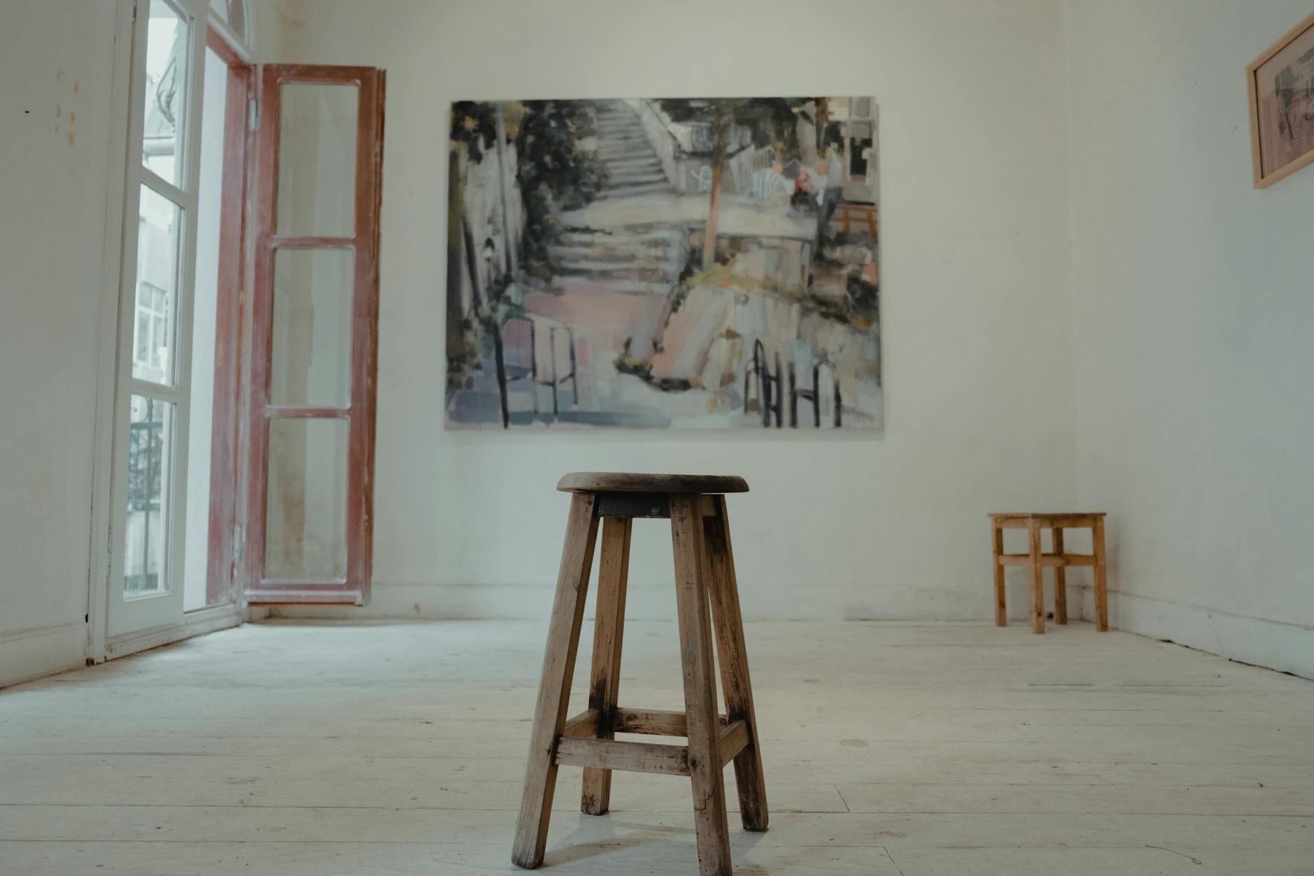 Drewniany stołek w minimalistycznej pracowni z abstrakcyjnym obrazem