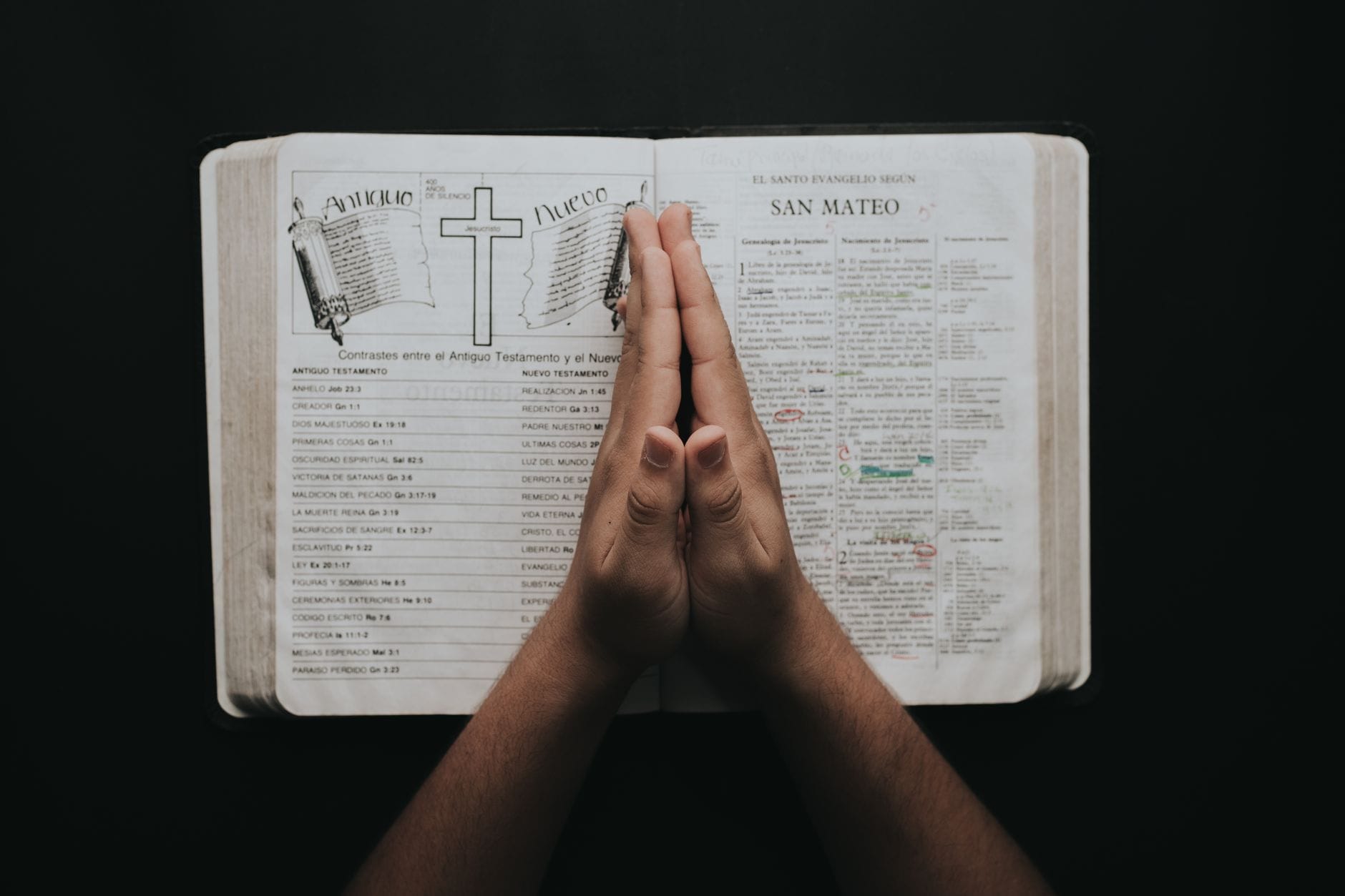Złożone dłonie na otwartej Biblii z Ewangelią Mateusza podczas modlitwy